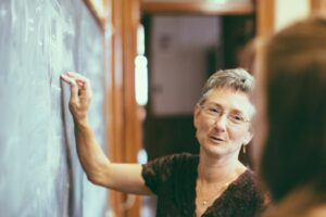 Female professor writing on chalkboard