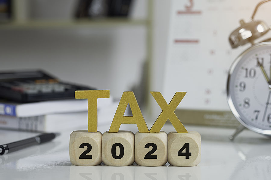 Tax and Vat 2024 Concept. Tax wooden letters on wooden cubes with 2024 on coins. income tax online return form for payment. Expenses, account, VAT, pay tax in 2024 year.